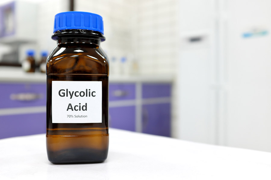 Selective focus of glycolic acid liquid solution in dark brown glass bottle in a white chemistry laboratory background. Chemical peel for skincare research.