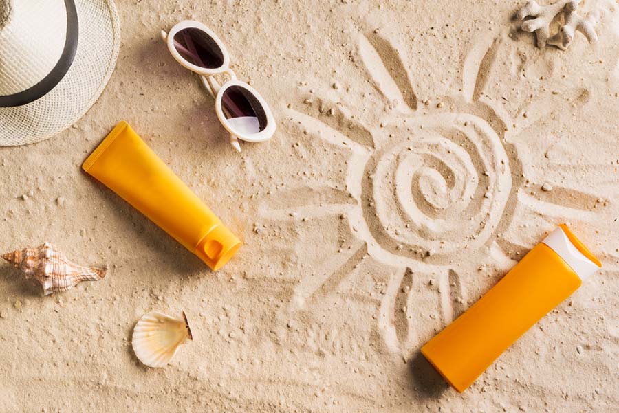 sun drawn in sand with sunscreen